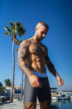 Kumsalda poz veren yakışıklı, kaslı bir adam.