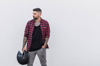 Gri renkte kaykayla poz veren şık ceketli yakışıklı dövmeli adam.