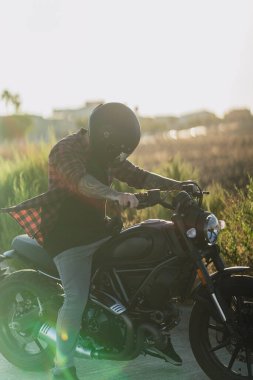 Motosiklet süren siyah elbiseli yakışıklı bir adam.