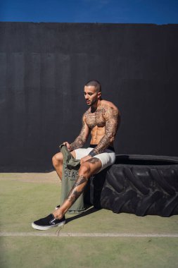 Kolunda dövmesi olan ve elinde topu tutan kaslı bir adam.