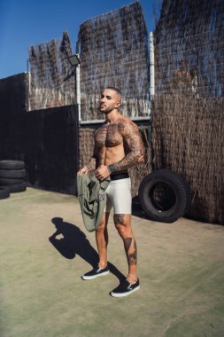 Parkta dövmesi olan yakışıklı, sakallı, kaslı adam.