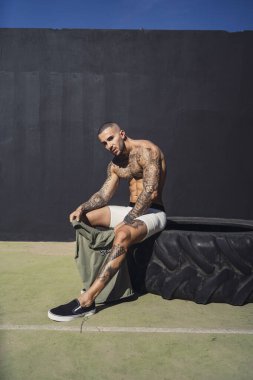 Siyah bluzlu, kaslı vücutlu yakışıklı atletik adam parkta egzersiz yapıyor. Sağlıklı yaşam tarzı ve spor kavramı