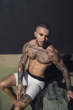 Beyaz iç çamaşırı ve kotlu yakışıklı kaslı adam spor salonunda poz veriyor.