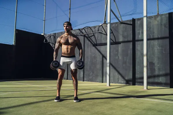 Siyah beyaz şortlu, elinde topu olan genç kaslı adam.