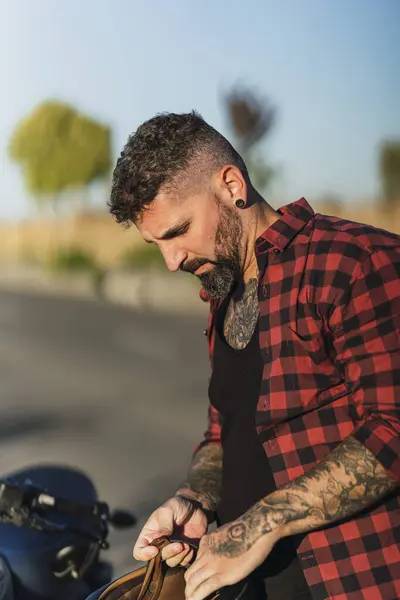 Motosikletli sakallı ve bıyıklı genç bir adam.