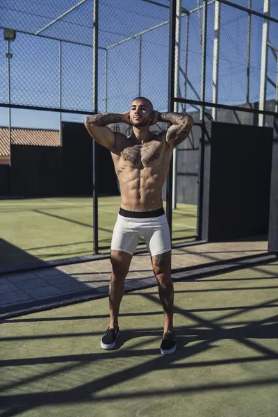 Siyah şortlu ve elinde top olan beyaz tişörtlü genç bir adam..