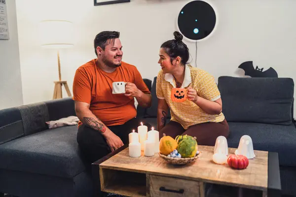 Evde kahve fincanları ve balkabaklarıyla mutlu genç bir çift