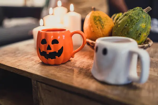 Bir fincan çay ve masada bir mumla balkabağının yakın plan fotoğrafı.