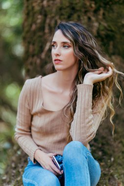 Dışarıda poz veren uzun kıvırcık saçlı güzel bir genç kadın.