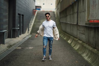 Sakallı genç adam şehir ortamında poz veriyor.