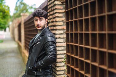 Sokakta siyah ceketli genç yakışıklı bir adam var.