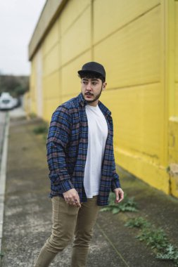 Şehirdeki sokaklarda poz veren uzun saçlı yakışıklı bir genç.