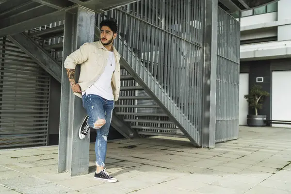 Modern binanın önünde poz veren sıradan giyinmiş yakışıklı bir adam.