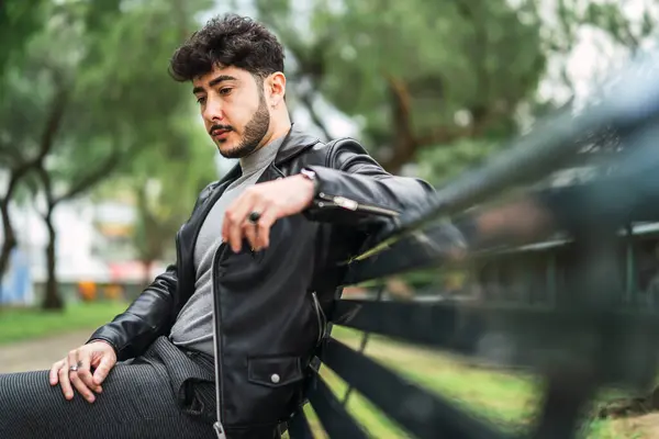 Deri ceketli ve siyah ceketli şık, genç sakallı adam sokakta poz veriyor.