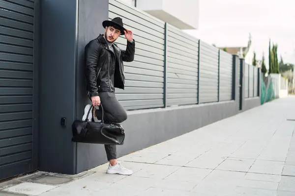 Siyah deri ceketli, güneş gözlüklü ve sokakta poz veren güzel bir kadının portresi.