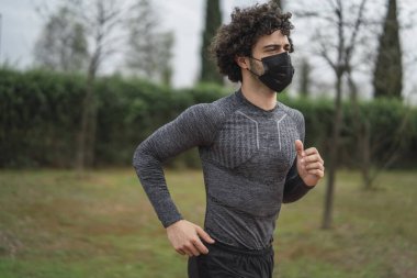 Korumacı maskeli bir adam sabah ormanda koşuyor.