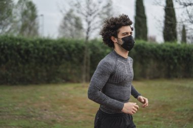 Parkta siyah bir maske takan genç adam.