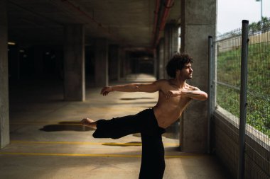 Genç adam şehirde yoga ve esneme pratiği yapıyor.