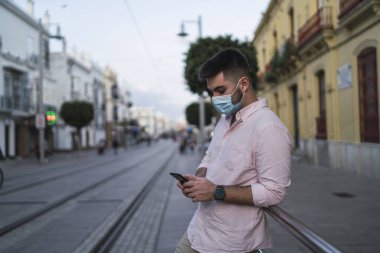 Şehir sokaklarında sosyal medya için cep telefonu kullanan genç adam