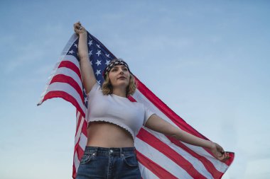 Amerika bayrağıyla gün batımında güzel genç bir kadın.