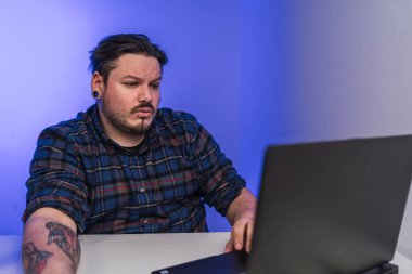 Ofisteki adam bilgisayarla uğraşıyor.