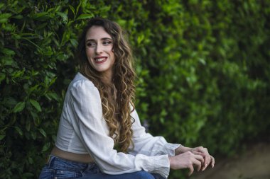 Genç ve güzel bir kadın parkta gülümsüyor..