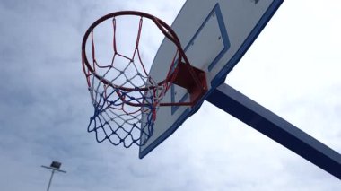 Bulutlu bir gökyüzünün arka planında mavi basketbol potası