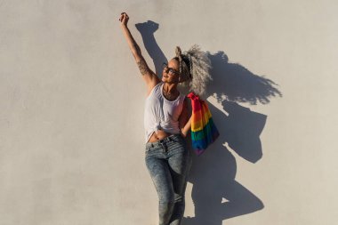 Gökkuşağı bayrağı ve gökkuşağı bayrağı taşıyan genç bir kadın