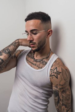 Dövmeli bir gencin portresi. Gri arka planda dövmesi ve dövmesi var..