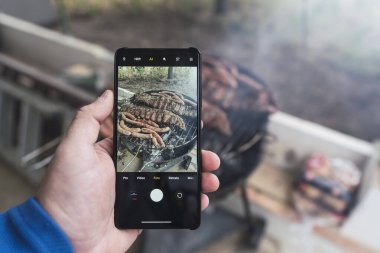 Elinde siyah fasulyeli akıllı telefon tutan adam.