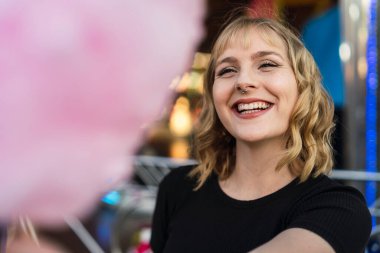 Eğlence parkında elinde şeker olan genç bir kadın.