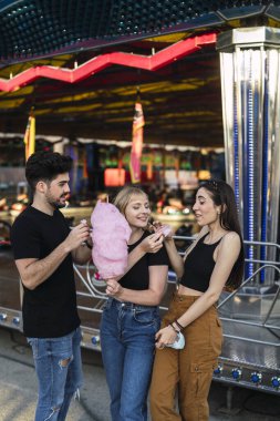 Bir grup arkadaş birlikte lunaparkta eğleniyorlar.