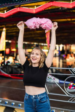 Eğlence parkında yüzünde kocaman bir gülümseme olan genç bir kadın.