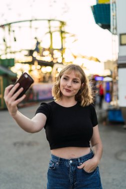 Lunaparkın arka planında selfie çeken kadın..