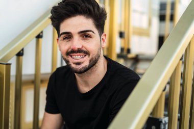 Şehirde sakallı, gülümseyen bir adamın portresi.