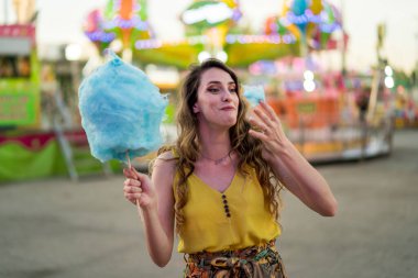 Genç kız lunaparkta şekerle eğleniyor, yaz tatilinin tadını çıkarıyor.