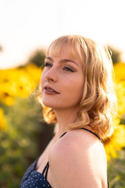 Sarı çiçeklerle poz veren genç sarışın kadın.