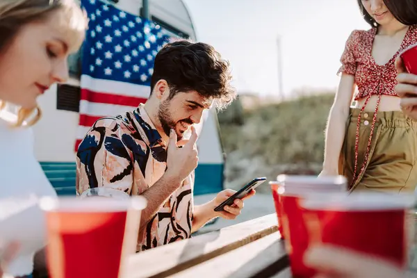 Mutlu genç arkadaşlar yaz aylarında bira içip cep telefonu kullanıyorlar.