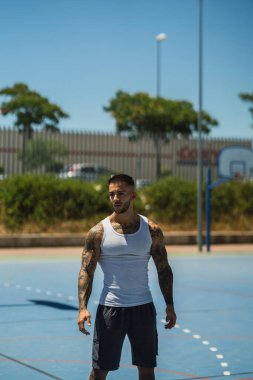 Spor giysileri içinde kaslı vücutlu yakışıklı genç adam parkta egzersiz yapıyor.