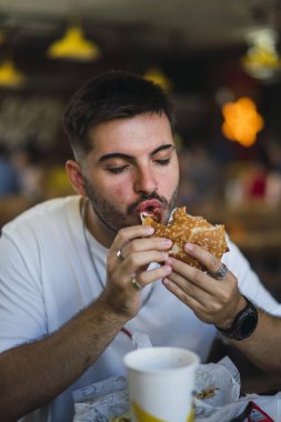 Genç sakallı adam fast food yiyor.