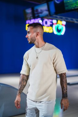 Beyaz gömlekli yakışıklı adam mavi ışıkların arkasında duruyor..