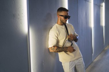 Şehirde kulaklıklı, güneş gözlüklü yakışıklı bir genç.