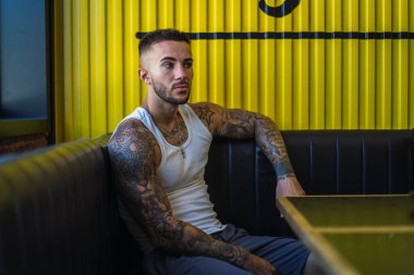 Barda oturan dövmeli yakışıklı adam.