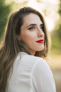 Kırmızı dudaklı, yeşil tişörtlü genç ve güzel bir kadın.