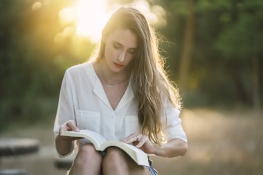 Parkta kitap okuyan kadın.