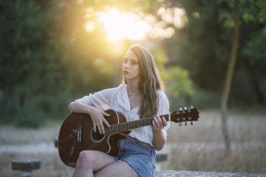Ormanda gitar çalan genç ve güzel bir kadın..