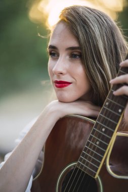 Gitarın yanında oturan kızıl saçlı güzel kız.