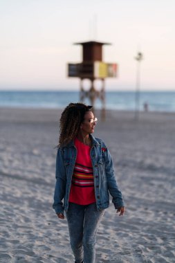 Güzel siyah kadın sahilde yürüyor.