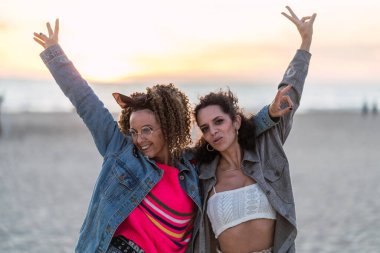 Gün batımında ellerle dans eden mutlu kadınlar.