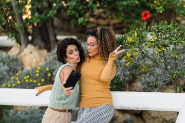 Parkta cep telefonu olan iki kadın.